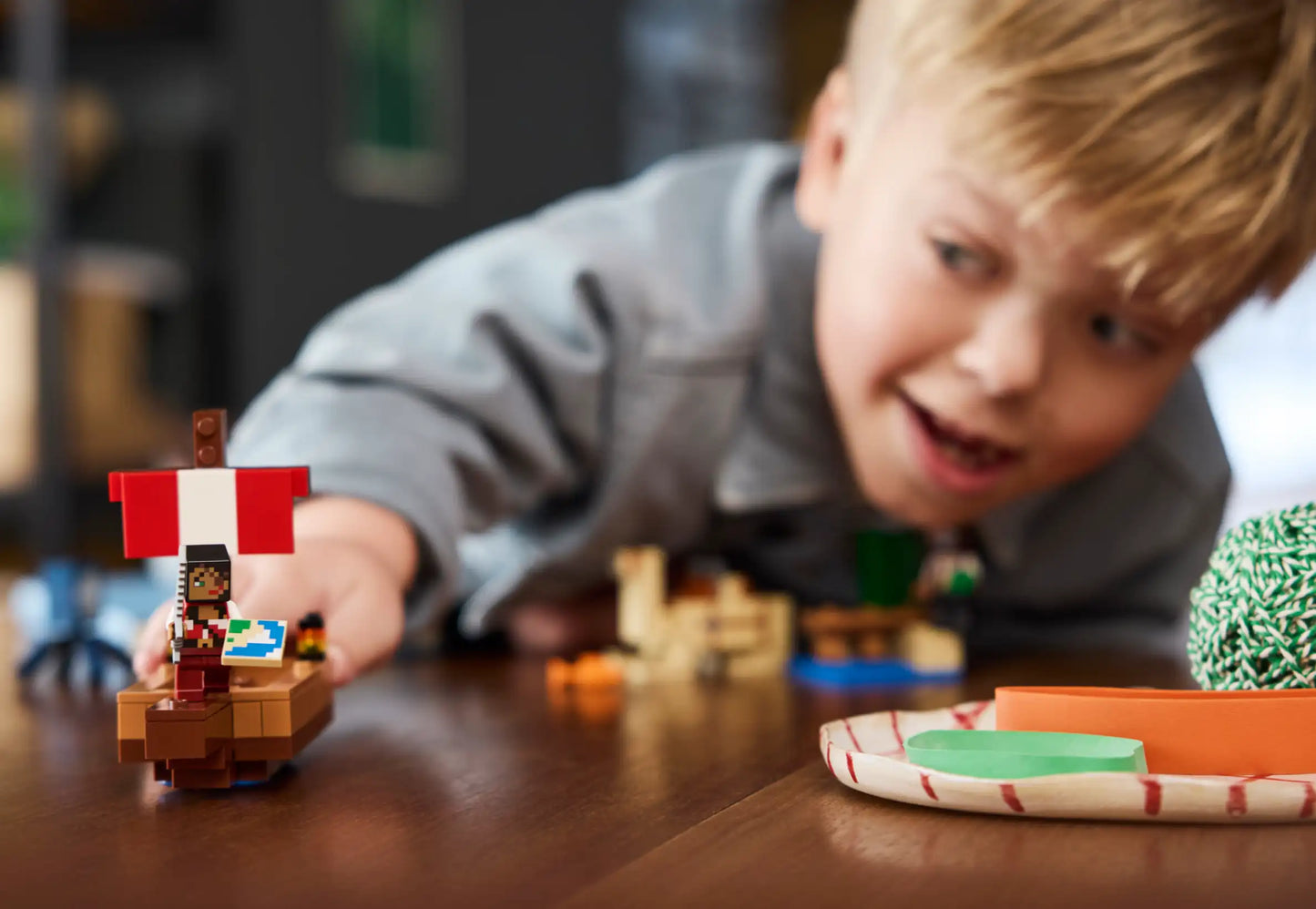 Child playing with a toy pirate ship on a wooden table