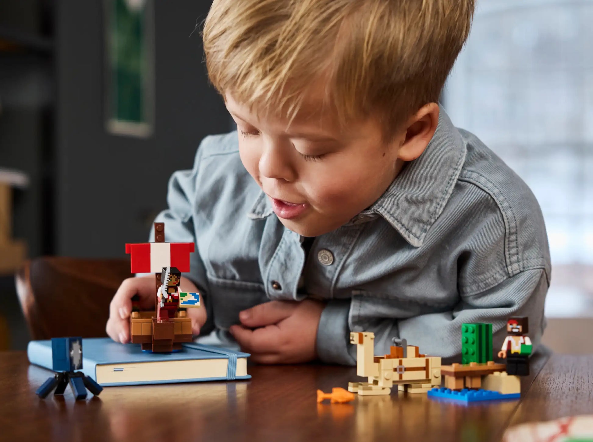Child playing with a pirate ship toy on a wooden table